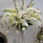 Tall centrepiece of white orchids and pale greens. Over a 1000 pearls in the vase with antique lace trim